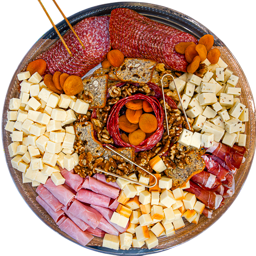A charcuterie platter arranged with cubed cheeses, sliced salami, rolled ham, prosciutto, dried apricots, mixed nuts, and artisanal crackers on a round serving tray.